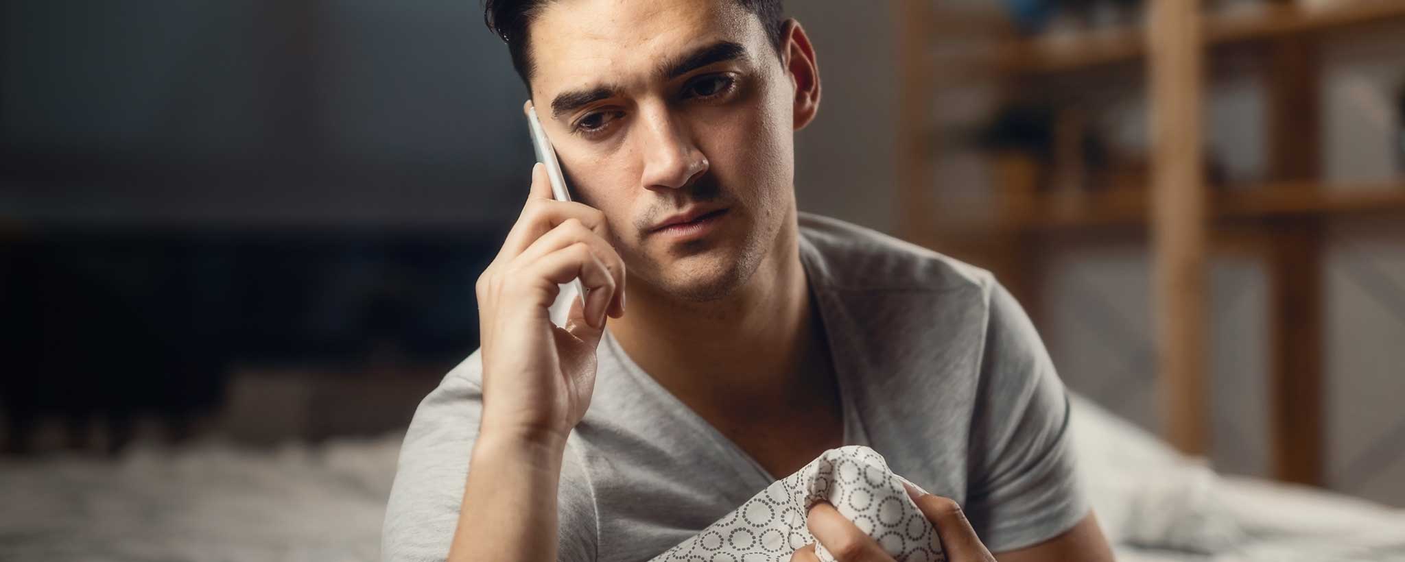 'A sad man holds a phone to his ear.'