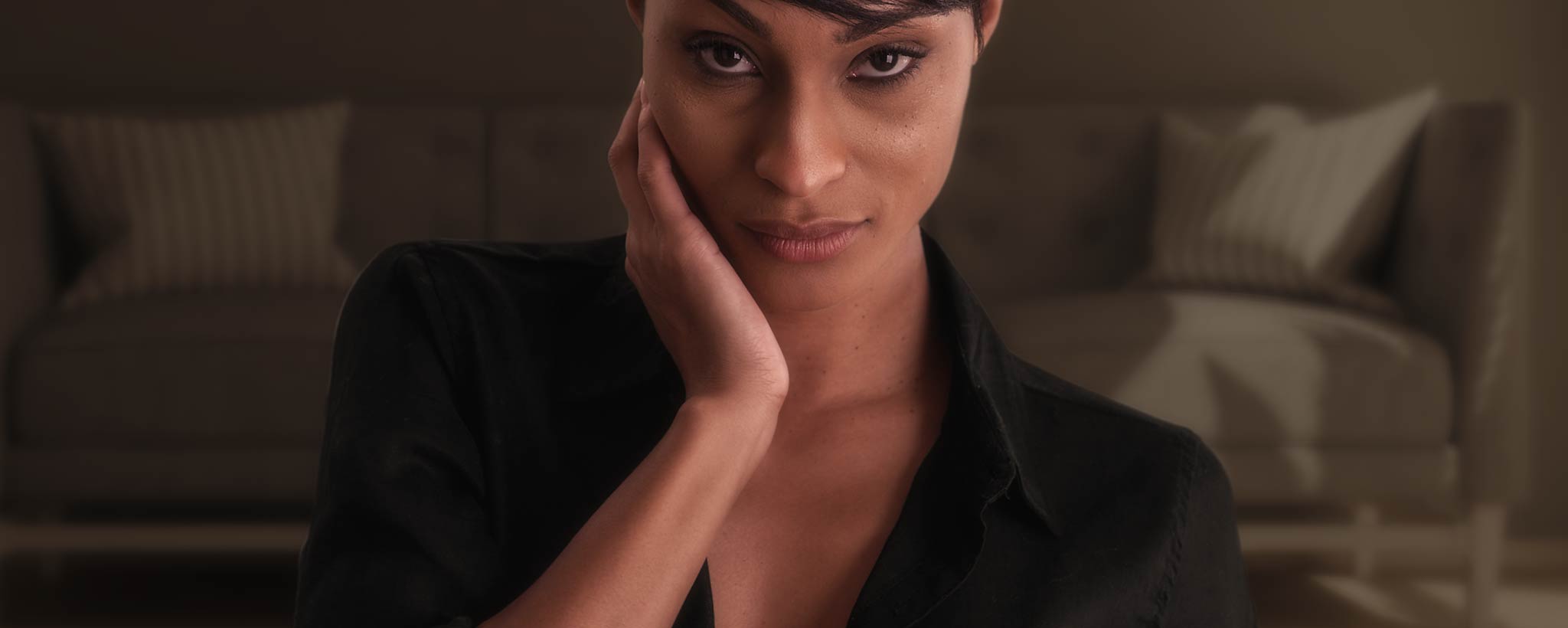 'An alluring Black woman holds her hand on her cheek.'