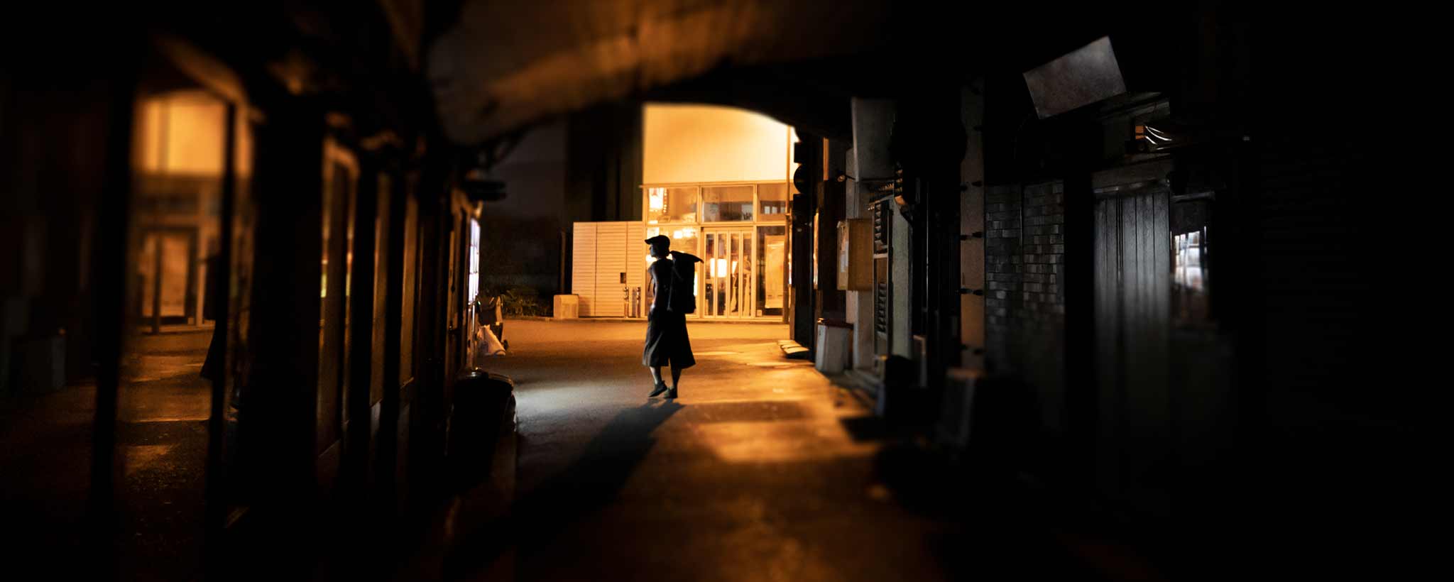 'A lone figure walking in shadowing darkness.'