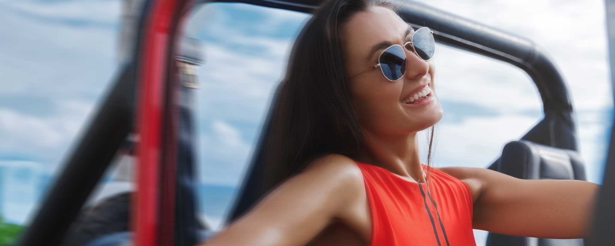 'Woman wearing sunglasses smiles in jeep'
