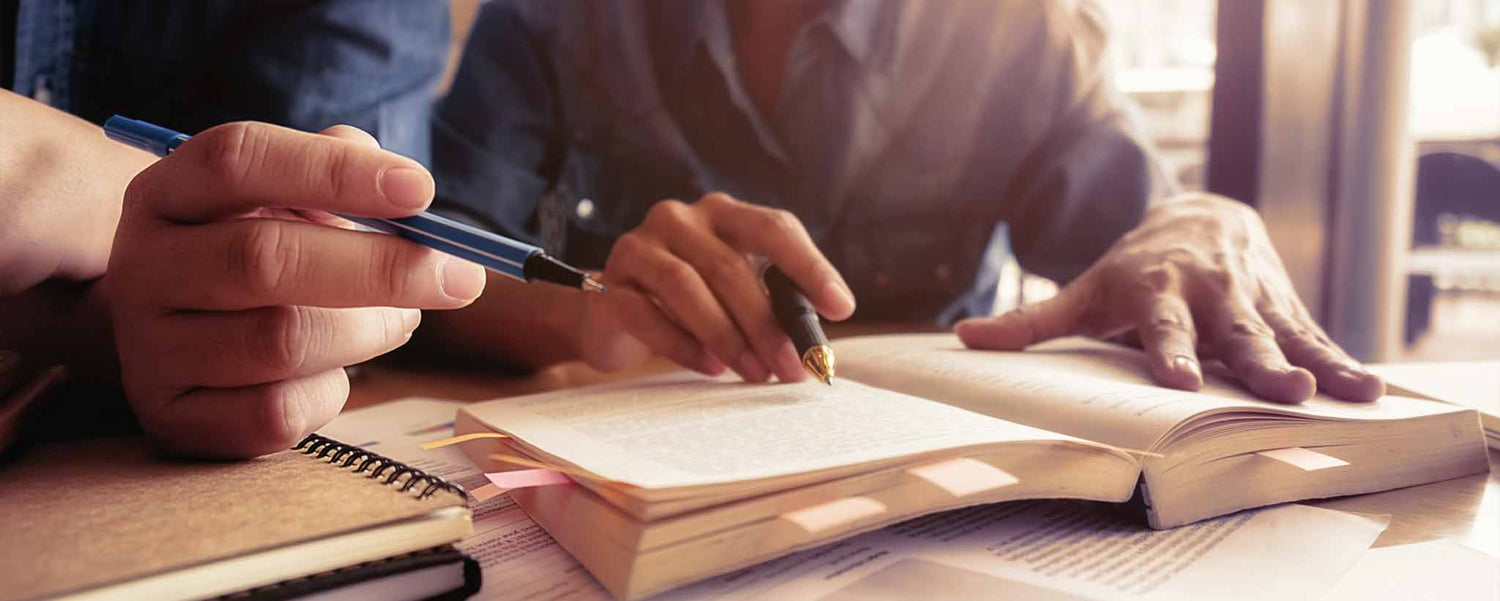 Hands of a couple studying books.