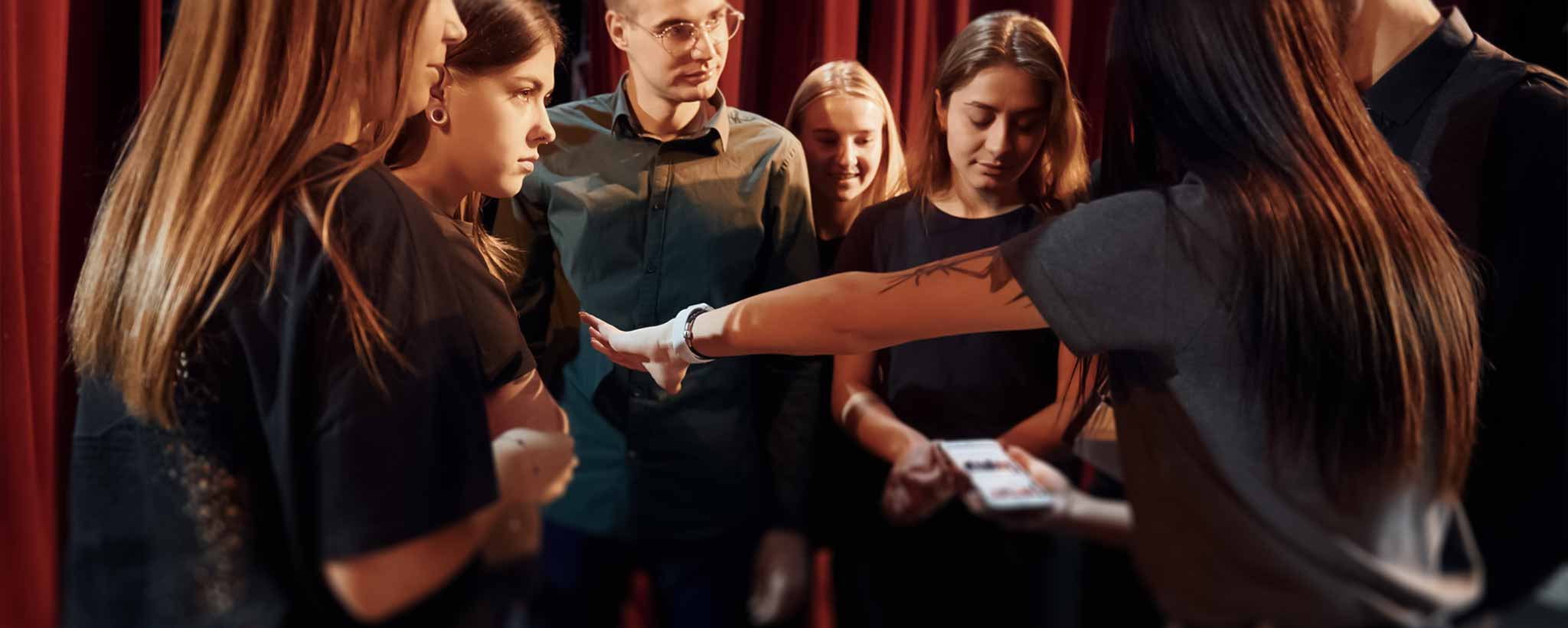 'A theater group is backstage receiving instructions from the director.'