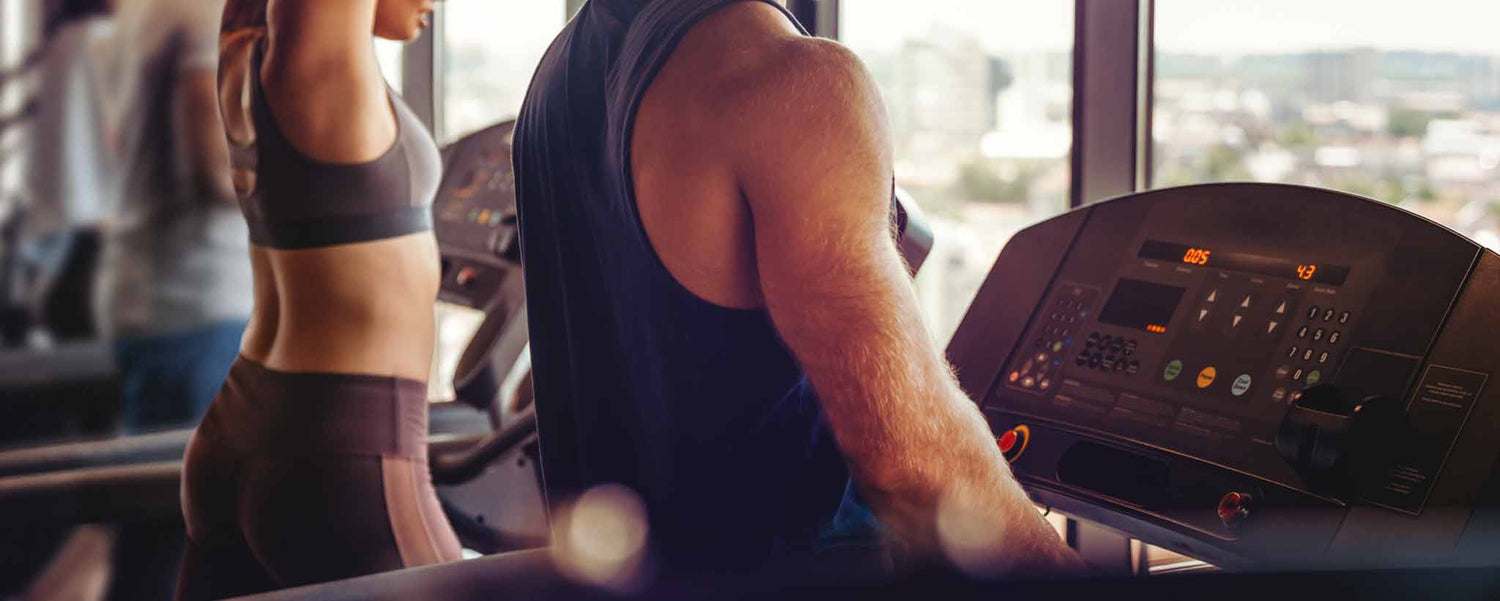 Male and female treadmill runners in a gym.