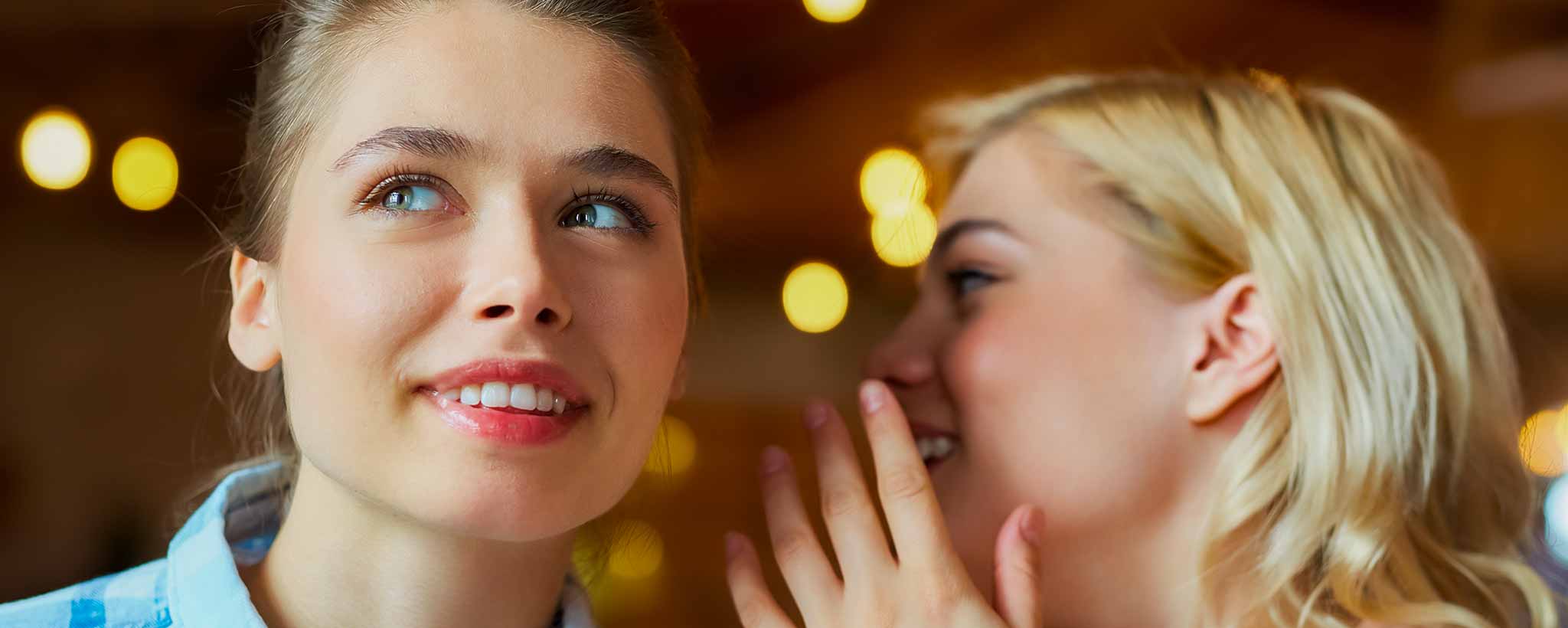 'Two ladies are engaged in a conversation with blurred lights in the background.'