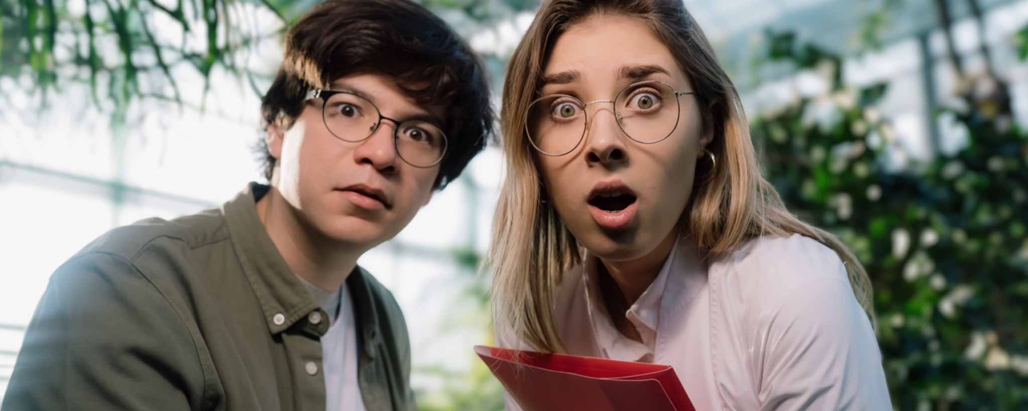 'Two people are reacting with surprise outdoors.'