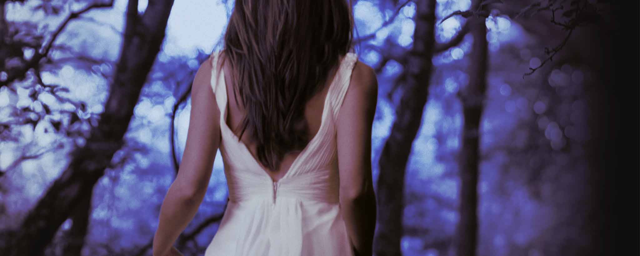 The back of a female wandering through the forest.
