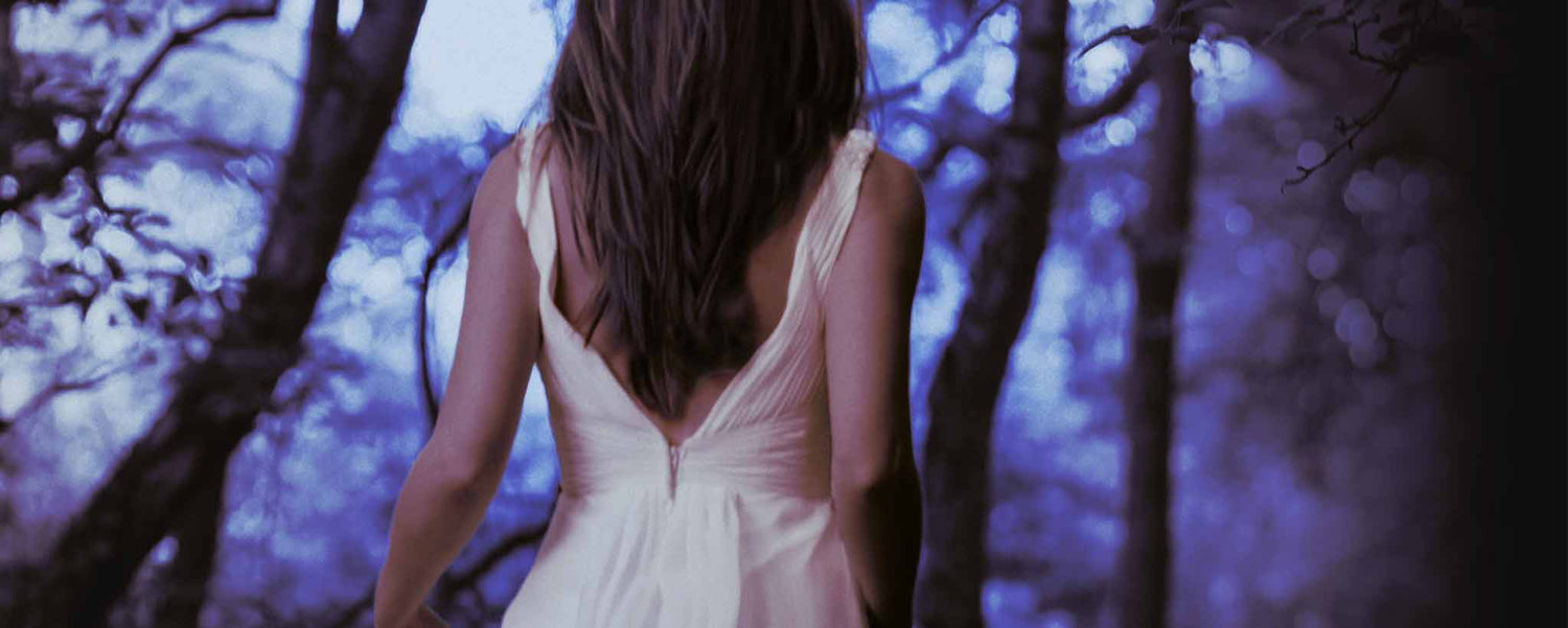 The back of a female wandering through the forest.