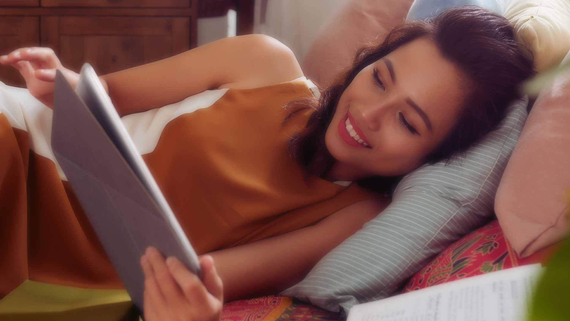 Smiling beautiful female reclining with digital tablet