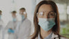 A nurse removes her surgical mask and glasses.